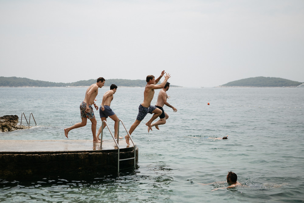 groom and groomsmen jumping in the water on a wedding day in Hvar Croatia
